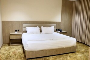 A hotel room with a large bed, a nightstand with a lamp, and a curtain. - Nasamat Silver Hotel (Madinah)
