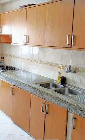 Una cucina con mobili in legno, un piano di lavoro in granito, una stufa a gas e un lavello in acciaio inossidabile.