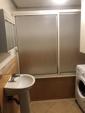 Un bagno con lavandino, lavatrice e porta scorrevole.