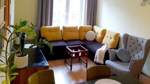 A living room with a sectional sofa, a grey armchair, a small table, and a potted plant. - W Sercu Olsztyna z Widokiem na Historię (Olsztyn)