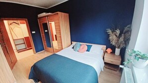 A bedroom with a bed, wardrobe, bedside table, and a potted plant. - W Sercu Olsztyna z Widokiem na Historię (Olsztyn)