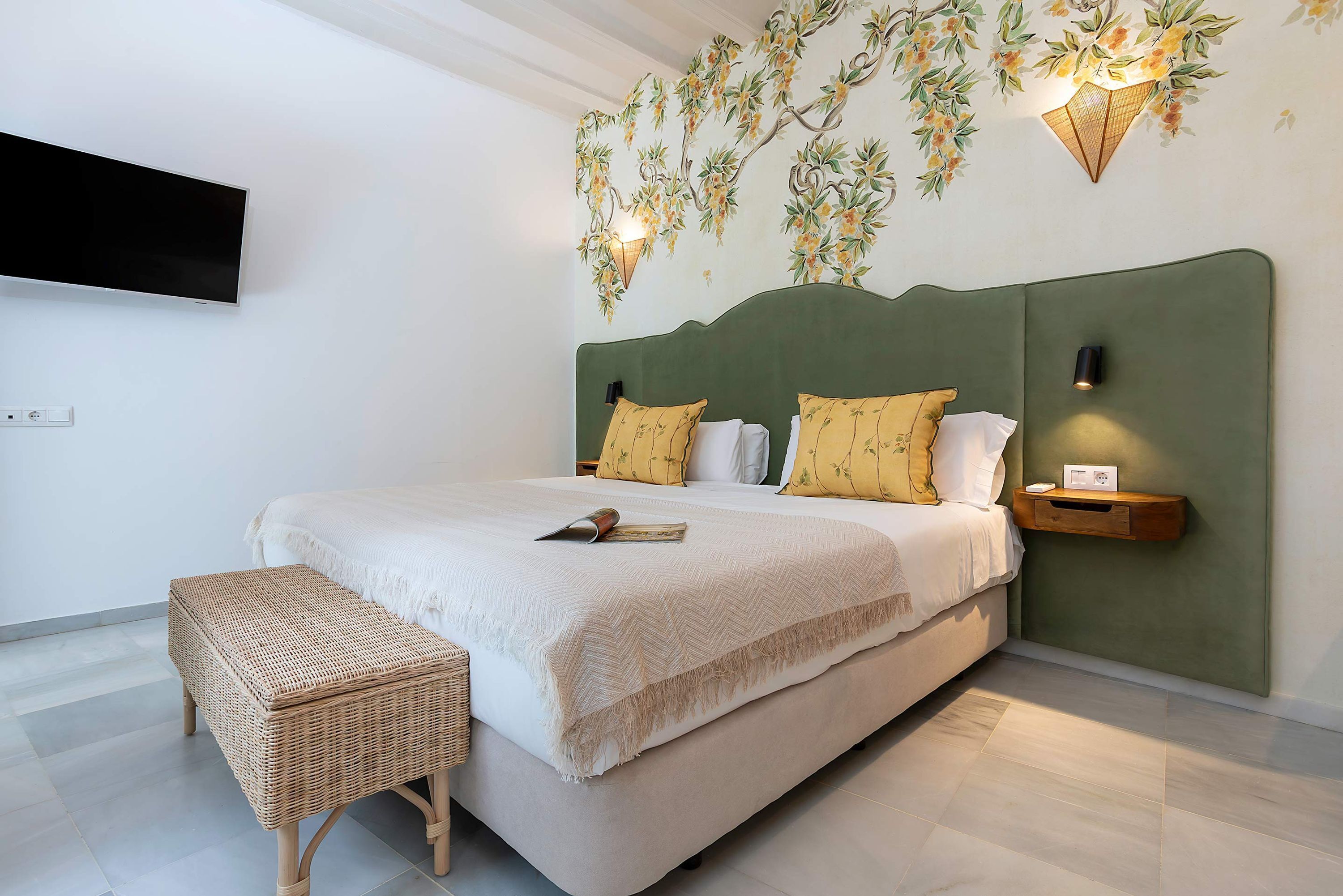 A bedroom with a bed, a bedside table, a wall-mounted TV, and a decorative wall piece.