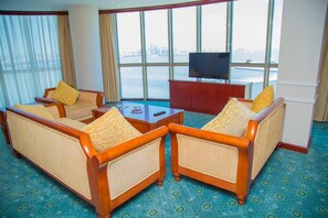 Una habitación de hotel con un ventanal grande, dos sofás, un televisor y una pequeña mesa.