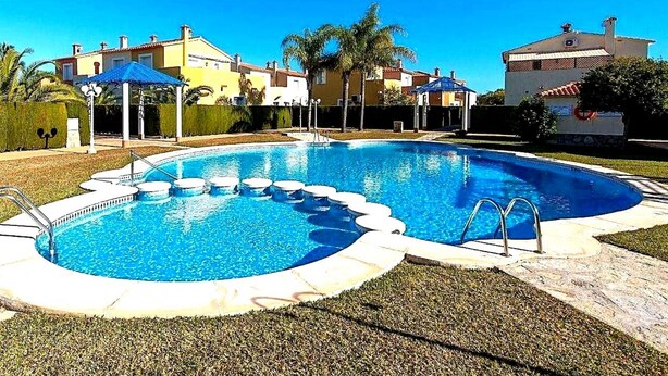 A swimming pool with a circular design, surrounded by a paved deck and palm trees. - Ad1600 in Oliva With 3 Bedrooms and 2 Bathrooms (Oliva)