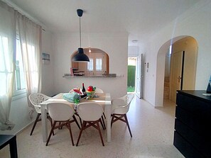 A dining area with a white table and chairs, a hanging light fixture, and a kitchen visible through an archway. - Ad1600 in Oliva With 3 Bedrooms and 2 Bathrooms (Oliva)