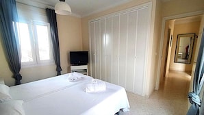 A hotel room with a large bed, a television, a wardrobe, and a hallway with a mirror. - Ad1600 in Oliva With 3 Bedrooms and 2 Bathrooms (Oliva)