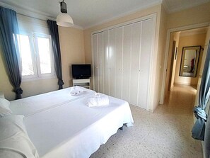 A hotel room with a large bed, a television, a wardrobe, and a hallway with a mirror. - Ad1600 in Oliva With 3 Bedrooms and 2 Bathrooms (Oliva)