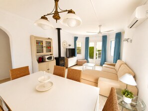 Ein modernes Wohnzimmer mit Sofa, Esstisch und Küchenzeile, inklusive Mikrowelle und Schränken.
