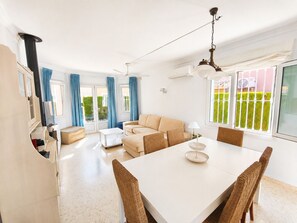 Ein modernes Wohnzimmer mit einer Couch, einem Esstisch und einem Fernseher.