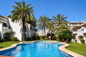 Ein Pool, umgeben von Palmen und weißen Gebäuden mit Rundbögen.