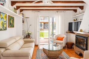 Ein Wohnzimmer mit einer Couch, einem Glastisch, einem Kamin und einem Fernseher.
