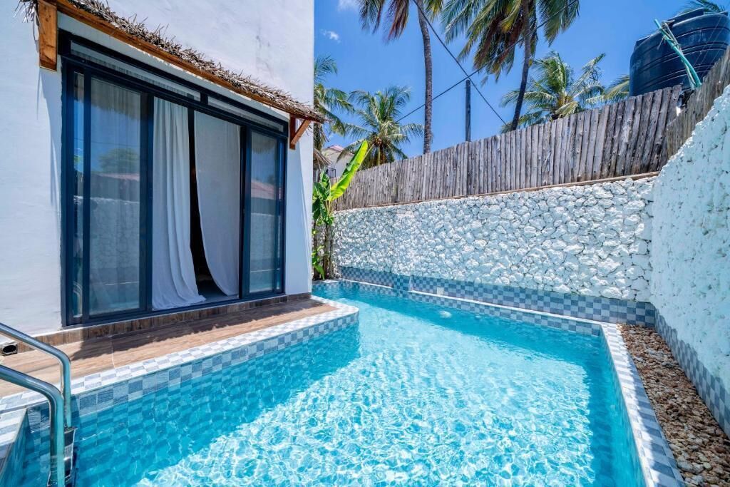 A swimming pool with a stone wall and a wooden fence.
