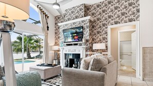 Ein Wohnzimmer mit Kamin, Fernseher und Blick auf einen Pool.