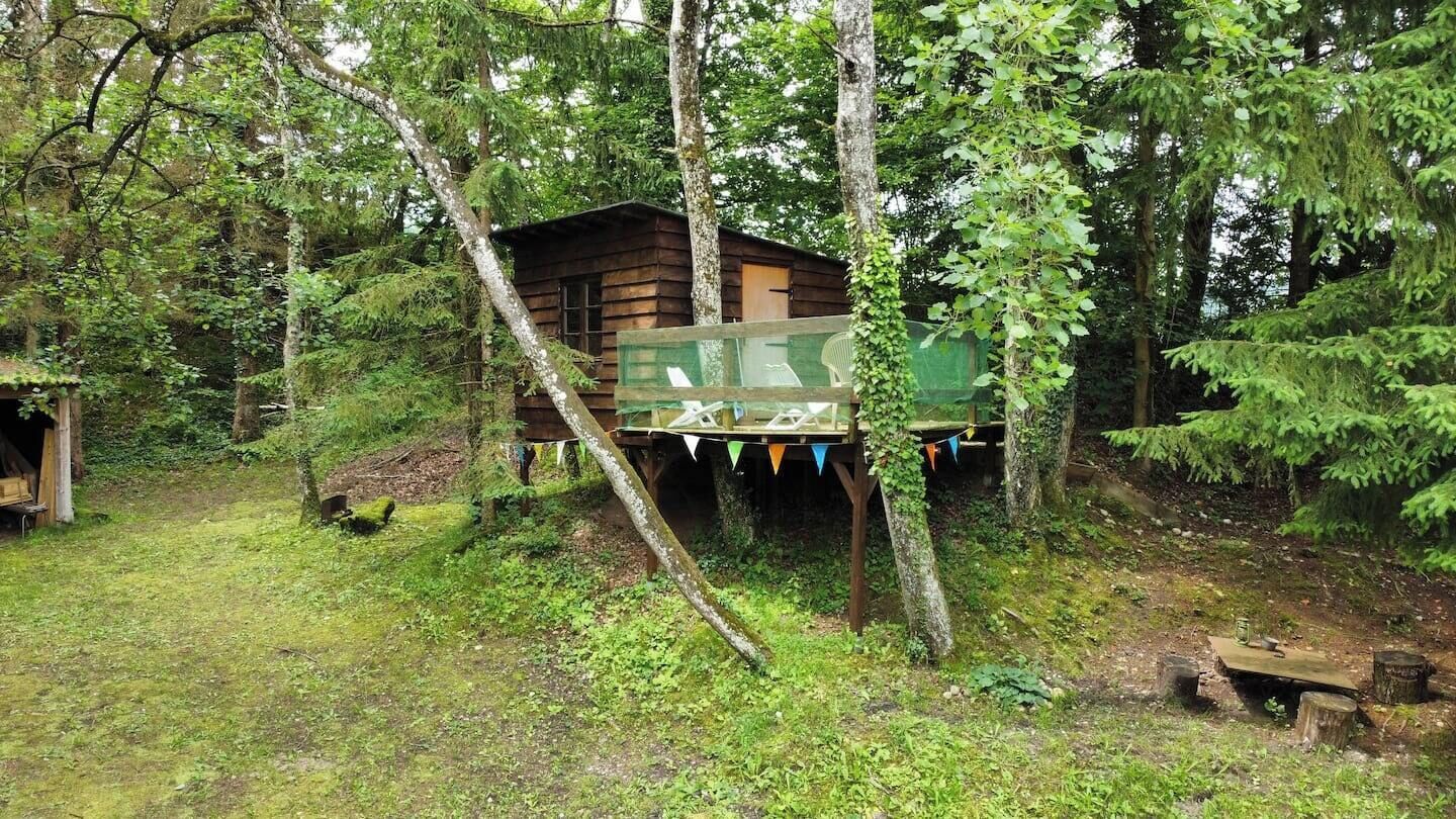 Una baita di legno con veranda, circondata da alberi.