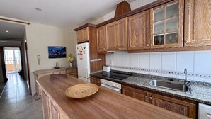 Cuina amb armaris de fusta, taulell de granat, forn de mur i rentapeus d'acer inoxidable.