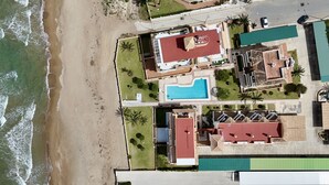 Vista aèria d'una propietat costanera amb piscina, diversos edificis i una platja.