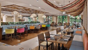 A spacious restaurant with multiple seating areas, including booths and tables, and large windows providing natural light. - Anantara Palm Jumeirah Luxury 1BR Sea View (Dubai)