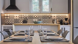 Una cuina moderna amb un mosaic decoratiu a la paret, una illa central i una zona de menjador preparada per a sis.
