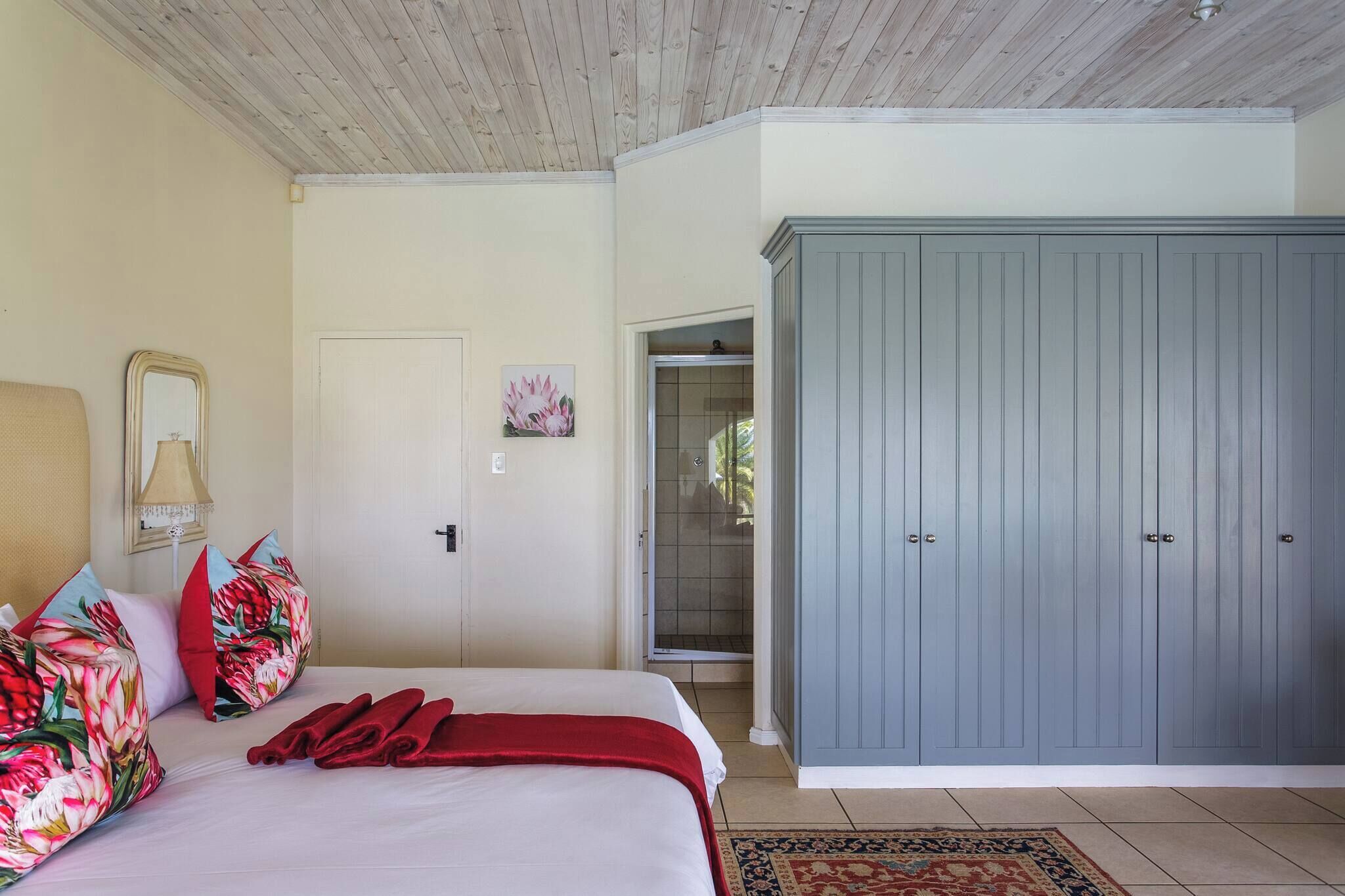 A bedroom with a bed, pillows, a wardrobe, and a shower area.