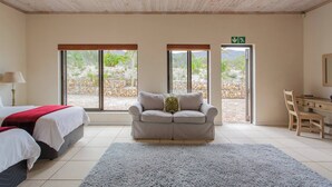 Ein Zimmer mit einem Bett, einer Couch, einem Schreibtisch und großen Fenstern.