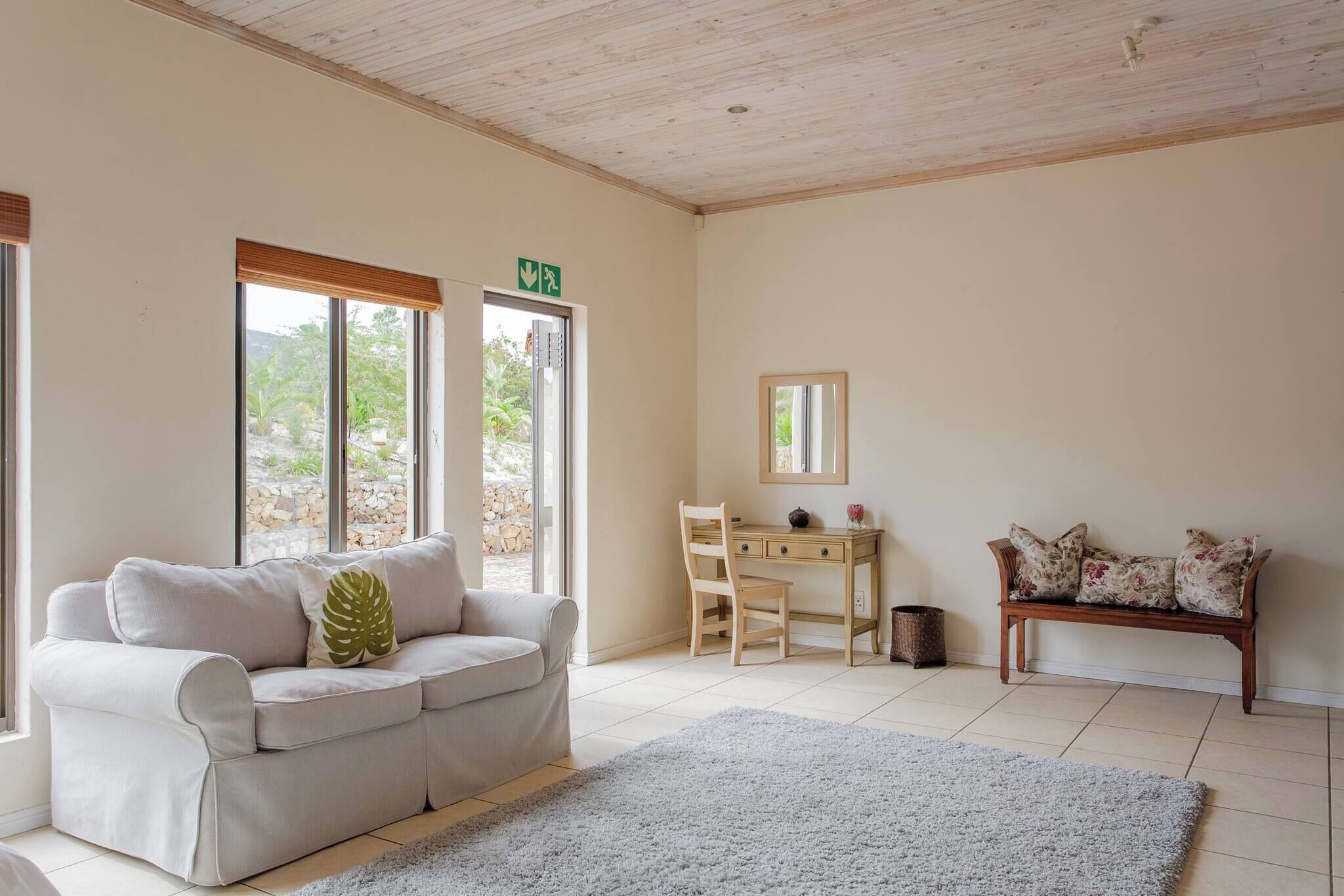 A room with a sofa, a desk, a chair, a bench, and a rug.