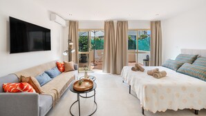 Een moderne hotelkamer met een bank, een bed, een televisie en uitzicht op de omgeving.