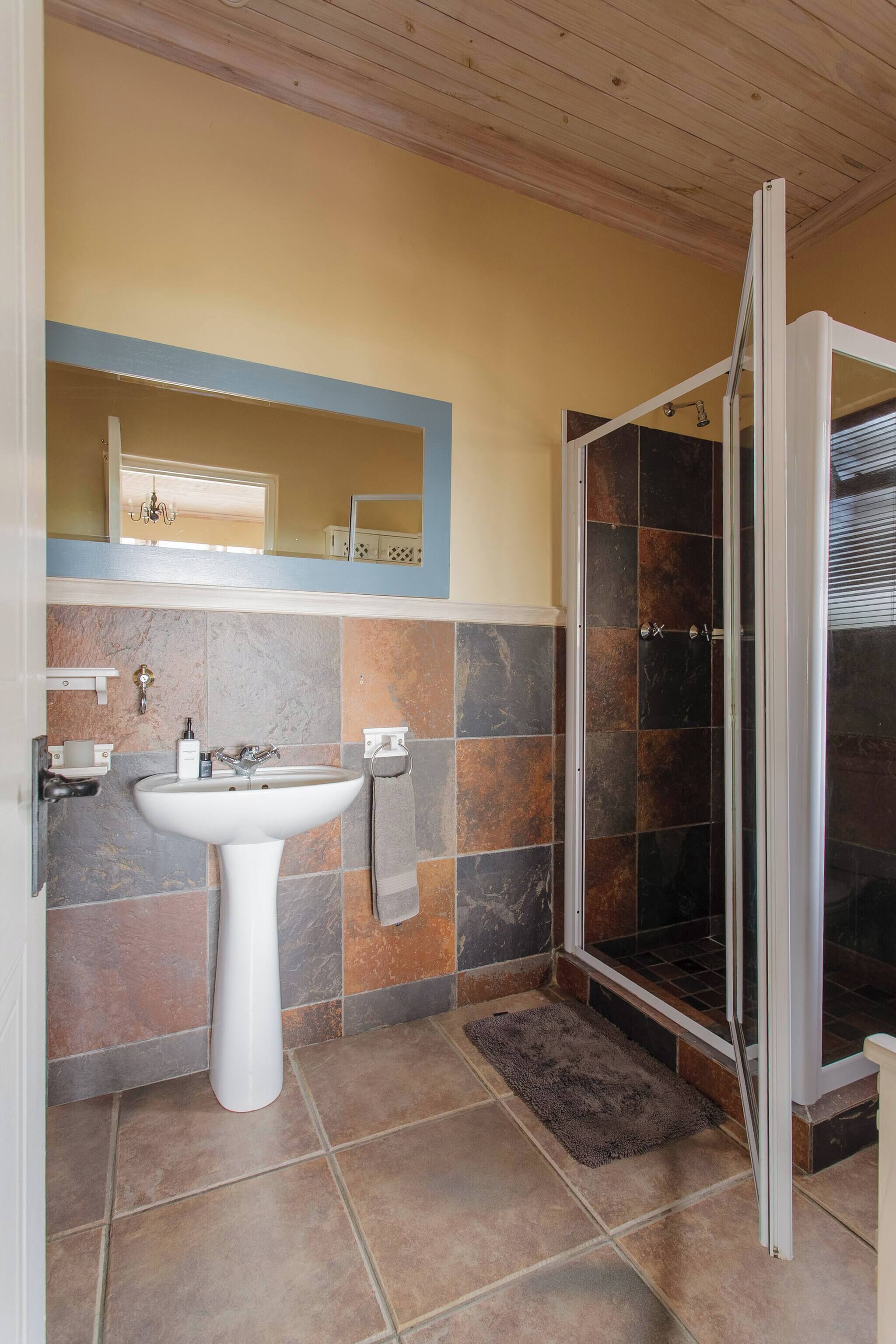 Une salle de bain avec un lavabo blanc, un miroir et un espace douche.