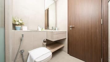 A bathroom with a toilet, a sink, a mirror, and a shower.