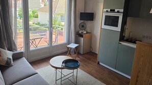 A compact living space with a balcony, kitchenette, and a sofa. - Modern and functional apartment near the beach and downtown (Paris)