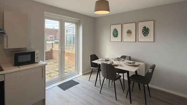 Una cucina moderna con un forno a microonde, un tavolo da pranzo per quattro persone e una porta vetrata scorrevole che dà su un giardino.