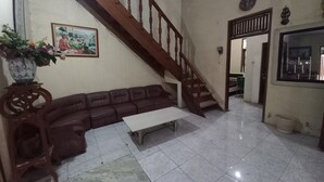 Uma sala de estar com escada de madeira, um sofá, uma mesa de centro e um quadro na parede.