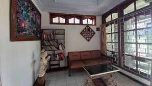 Uma sala de estar com sofá, mesa de centro de vidro, estante e uma escultura decorativa.
