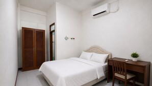Quarto com cama, escrivaninha, cadeira, guarda-roupa e ar condicionado.
