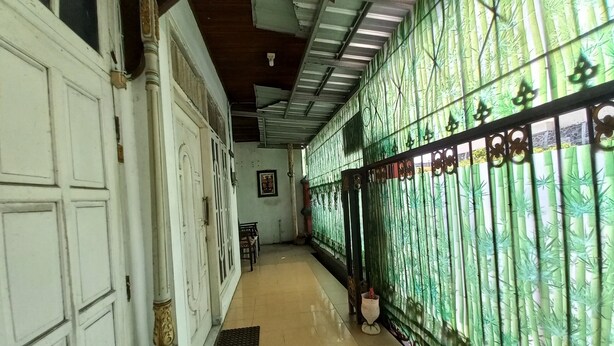 Um corredor com piso ladrilhado, portas brancas e um cercado verde com padrão.