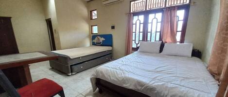 Un dormitorio con cama, escritorio, silla y ventana con cortinas.