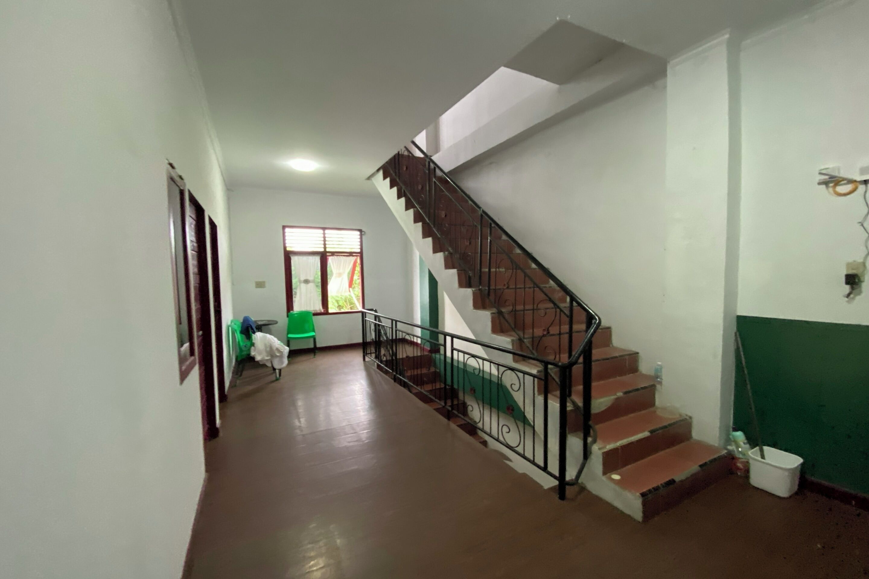 Un pasillo con escaleras, una puerta y una ventana con persianas.