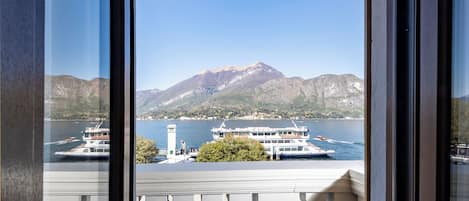 A balcony with a view of a lake, boats, and mountains.