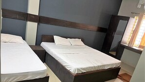 A hotel room with two beds, a dark headboard, a window with curtains, and a tiled floor. - Mysuru Dine  (Mysore)