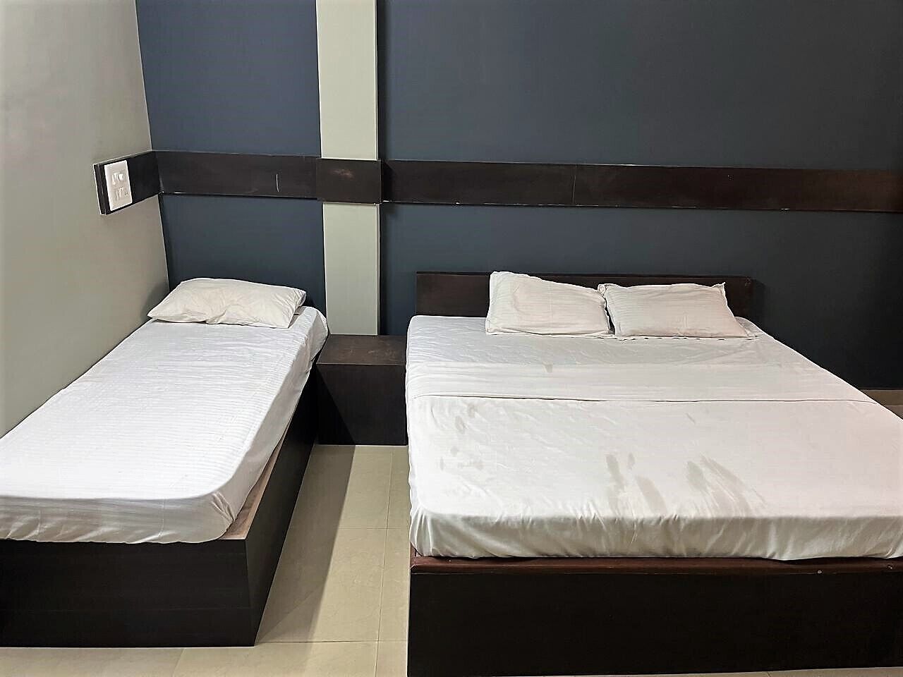 Two single beds with wooden headboards, white bedding, and a nightstand between them.