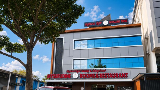 A modern building with a sign for Mysuru Dine Restaurant and Rooms & Restaurant. - Mysuru Dine  (Mysore)