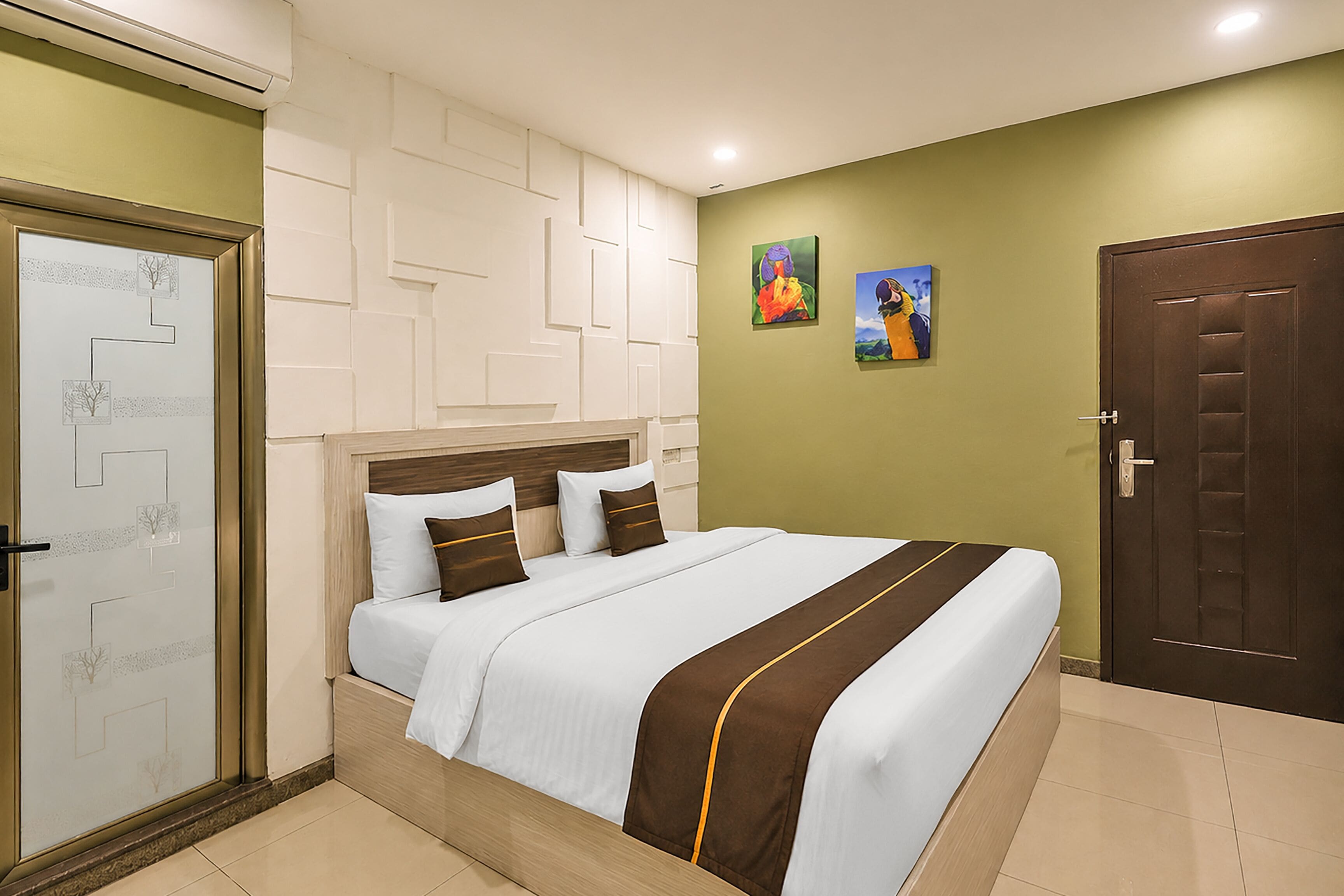 A hotel room with a bed, a door, and a wall with artwork.