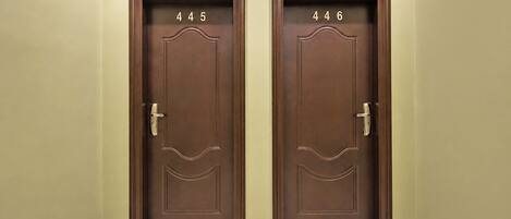 Two identical brown doors with numbers 445 and 446, each with a door handle and a keyhole.