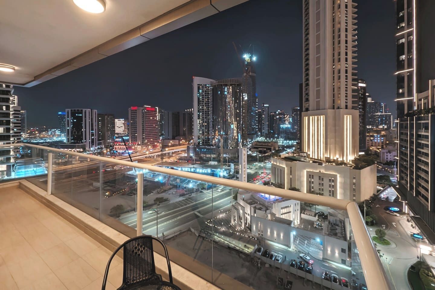 A high-rise building with a view of a cityscape at night, including illuminated buildings and a busy road.