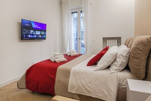 Een hotelkamer met een bed, een aan de muur bevestigde televisie, een raam met gordijnen en een radiator.