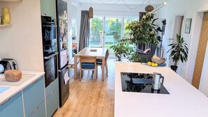 Moderni keittiö, jossa on ruokailutila, puulattia ja suuret ikkunat.