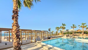 A poolside area with lounge chairs, a palm tree, and a clear blue sky.