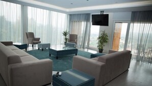 Ein modernes Wohnzimmer mit einer Sofagarnitur, einem Couchtisch und einem an der Wand befestigten Fernseher.