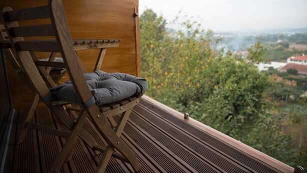 Eine Holzterrasse mit einem Klappstuhl und Blick auf eine grüne Landschaft.