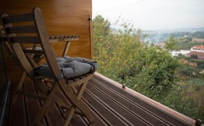 A wooden deck with a folding chair and a view of a green landscape. - Casa de Campo Memórias da Comarca (Arganil)