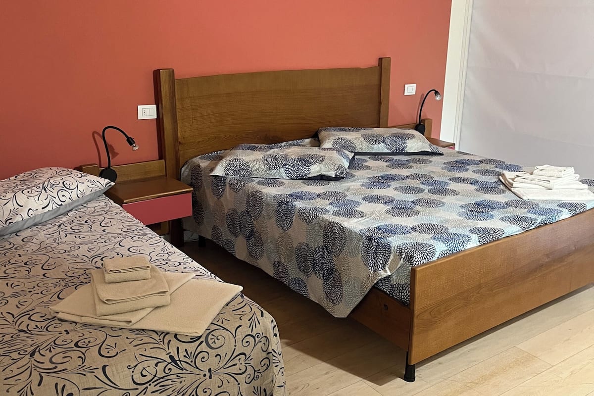 Un dormitorio con dos camas, cabeceros de madera, mesitas de noche, una lámpara y una toalla doblada en el suelo.